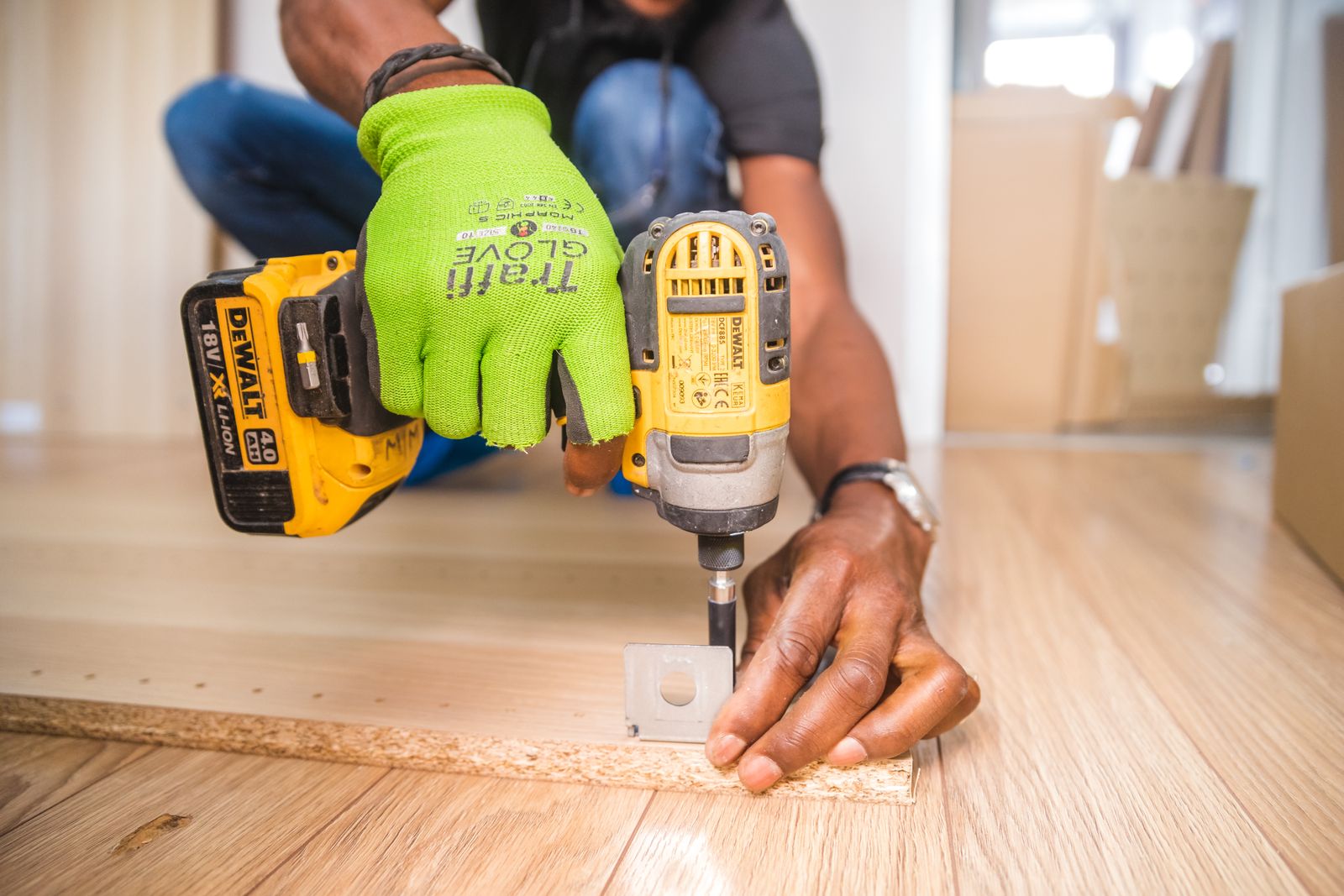 Hände eines Möbelmonteurs führen ein Holzstück an der Bank